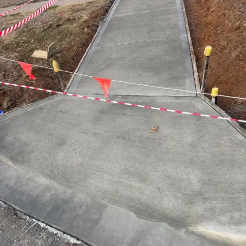 Newly constructed concrete footpath with red warning flag
